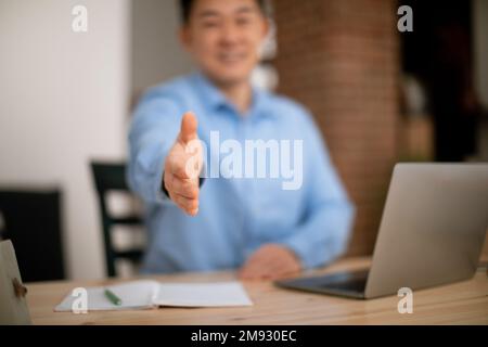 Partnership concept. Asian male entrepreneur extending hand for handshake at camera, selective focus Stock Photo