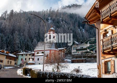 Moena, Dolomites, Italy, January 16th 2023. Fresh morning snow on the rooftops of cottages and Chiesa di San Giuseppe. Stock Photo