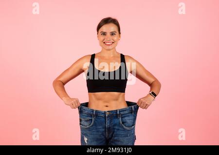 Weight Loss Result. Happy Slim Beautiful Woman Wearing Oversized Jeans Stock Photo