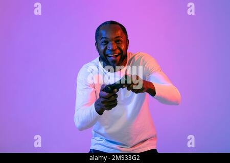 Excited black man playing video games, holding joystick Stock Photo