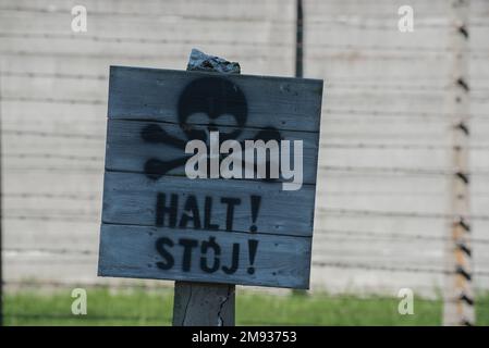June 15 2022: Auschwitz, Poland. warning Sign board about Electrified fence in Concentration Camp. There More than three million people were murdered Stock Photo