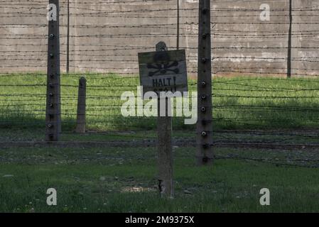 June 15 2022: Auschwitz, Poland. warning Sign board about Electrified fence in Concentration Camp. There More than three million people were murdered Stock Photo