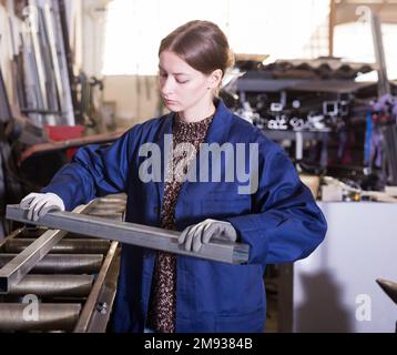 Female worker controlling quality of metal parts Stock Photo
