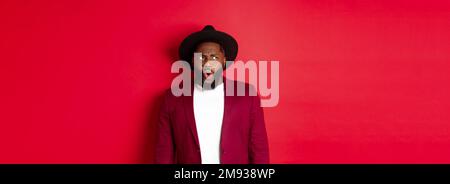 Fashion and party concept. Shocked and displeased black man staring at something unpleasant, looking upper left corner and frowning, standing against Stock Photo