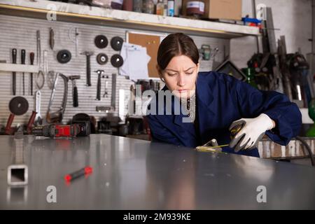 Woman working with metal sheet and using measuring tape Stock Photo