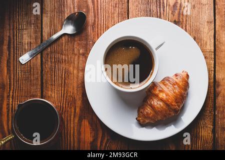 Fresh Croissant and Cup of Coffee on Wooden Surface. View from Above Stock Photo