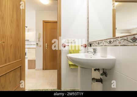 Bathroom with one-piece white porcelain pedestal sink and wall-mounted mirror with valance frame Stock Photo