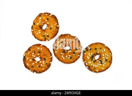 Salted round pretzels with black and white sesame isolated on white. Cracker chips with sea salt isolated on white background. Round shape appetizers. Stock Photo