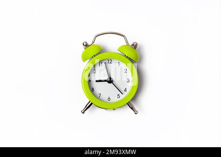 Beautiful lime green metal alarm clock isolated on white background. Concept of time. On the clock face, it's five minutes to nine in the morning Stock Photo