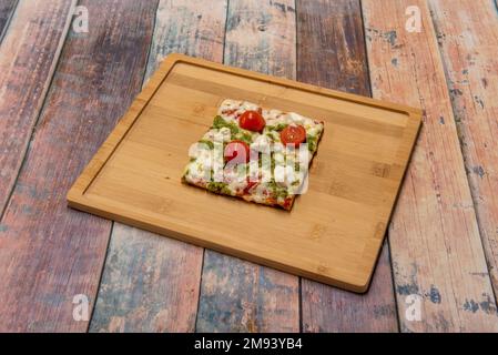 A slice of individual square cherry tomato pizza, cheese with pesto sauce Stock Photo