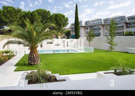 Beautiful swimming pool of a luxury detached house with marble tiles and a wall with niches to accommodate outdoor plants, stairs of the same material Stock Photo