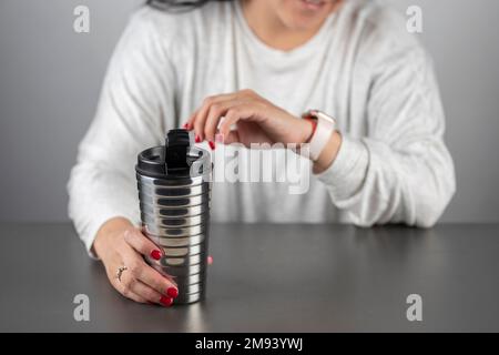 Unrecognizable woman reading while holding a cup of coffee, at home in the morning. Stock Photo