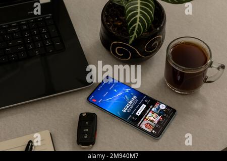 Mexico, CDMX - May 01, 2022: Netflix open on a cell phone screen on a desk with a computer, coffee and car keys. Stock Photo