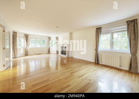 Large empty living room with marble fireplace, aluminum radiators and many French-style aluminum windows Stock Photo
