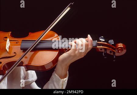 Close-up of a woman playing a violin with hands on the strings Stock Photo