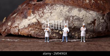 Roasted bread and three miniature chefs. Miniature people and business concept. Stock Photo