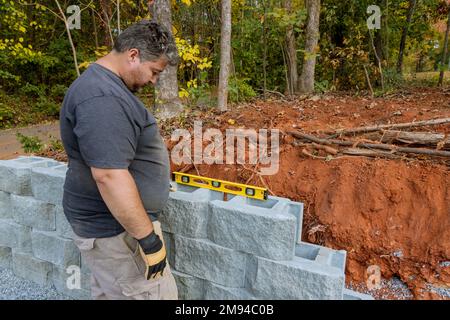 Following leveling of walls on construction site retaining wall contractor installed concrete block. Stock Photo