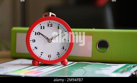 Alarm clock on financial document with charts and graphs. Stock Photo