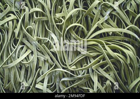 Fresh pasta. Homemade italian raw fettuccine pasta with spinach on wooden table background. High quality photo Stock Photo