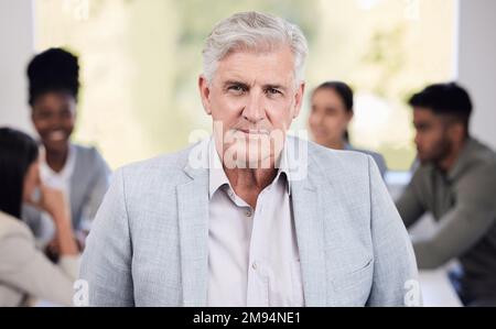 A person who is quietly confident makes the best leader. Portrait of a senior businessman standing in an office with his colleagues in the background. Stock Photo