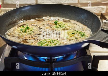 Grated potato dish - Draniki are fried in frying pan on gas stove at home in the kitchen Stock Photo