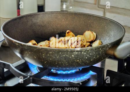 Sliced potatoes are fried in frying pan on gas stove Stock Photo