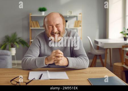 Happy smiling senior man sitting at table at home Stock Photo