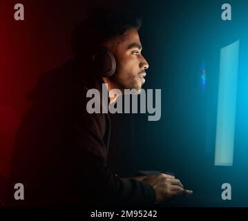 Focused on winning. a handsome young male gamer playing video games in a dark room. Stock Photo