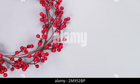 Colorful background with strips of red berry garland on grey. Festive Christmas birthday decoration garland. Space for text Stock Photo