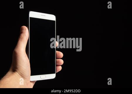 Smartphone with black screen in hand isolated on black background Stock Photo