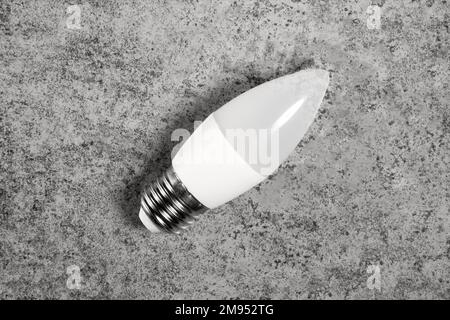 LED energy-saving lamp with E27 screw cap base in form of candle, on gray background Stock Photo
