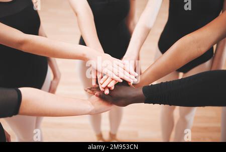 Coming together as one. a group of ballet dancers joining their hands together in unity. Stock Photo