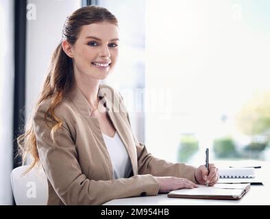 Staying organised is key to staying ahead. Portrait of a young businesswoman writing notes while working in an office. Stock Photo