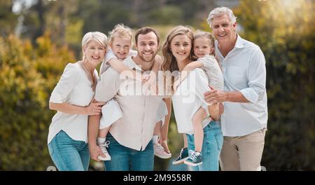 Portrait of multi-generation family standing together. Extended caucasian family smiling while spending time together at the park on a sunny day Stock Photo