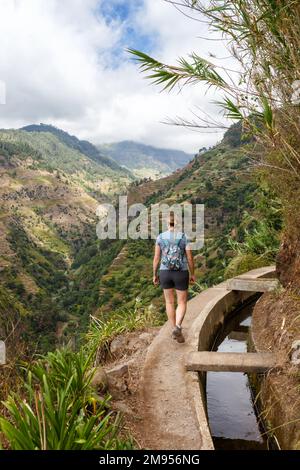 Young woman on hiking trail along Levada Nova portrait format travel hike tour on Madeira island in Portugal Stock Photo