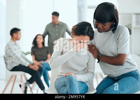 I keep making the same mistake. an attractive young woman sitting and comforting a member of her support group. Stock Photo
