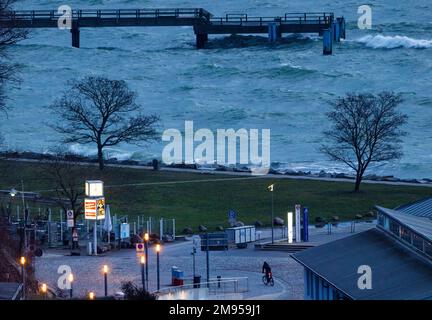 Sassnitz, Germany. 17th Jan, 2023. A cyclist is on the road in the city harbor in the morning. Stormy and chilly winter weather is currently showing up in northern Germany. Credit: Jens Büttner/dpa/Alamy Live News Stock Photo