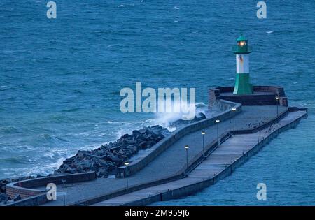 Sassnitz, Germany. 17th Jan, 2023. Waves break before sunrise at the harbor entrance at the pier with the flashing lighthouse. Stormy and chilly winter weather currently appears in northern Germany. Credit: Jens Büttner/dpa/Alamy Live News Stock Photo