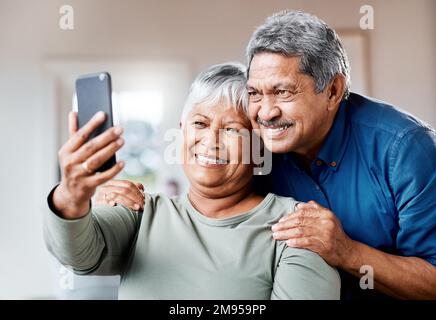 Beautiful portrait. a happy senior couple using a cellphone for a selfie together at home. Stock Photo