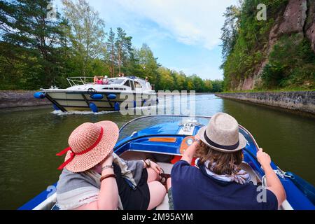 Couple on a boat trip, VINTAGE electric boat and barge with tourists moving in opposite direction on the Canal de la Marne au Rhin (Marne-Rhine Canal) Stock Photo