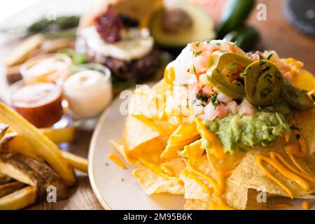 Nachos with guacamole. Nachos are a dish of Mexican origin, which consists of frying pieces of corn tortilla covered with a special cheese. Stock Photo