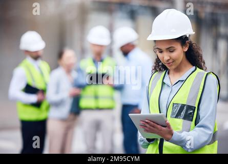 I can just check that on my tablet. a young female architect using a digital tablet at a building site. Stock Photo