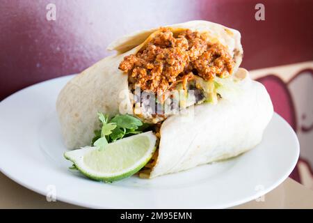 A burrito is a dish of Mexican and Tex-Mex cuisine that was formed in Ciudad Juárez and consists of a flour tortilla wrapped in a sealed cylindrical Stock Photo