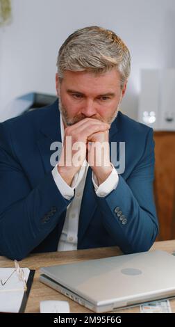 Stressed sad mature businessman losing job having financial problems at office workplace. Frustrated middle aged gray-haired freelancer man thinking of money debt, budget loss bankruptcy. Overworking Stock Photo