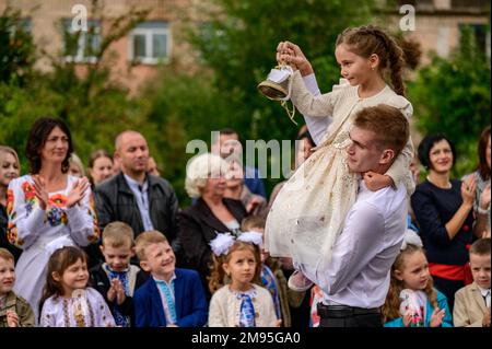 Ivano Frankivsk, Ukraine September 1, 2021: the holiday of the first bell in Ukraine, a high school student carries a girl on his shoulders who holds Stock Photo
