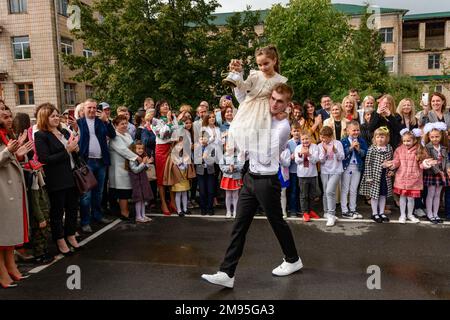 Ivano Frankivsk, Ukraine September 1, 2021: the holiday of the first bell in Ukraine, a high school student carries a girl on his shoulders who holds Stock Photo
