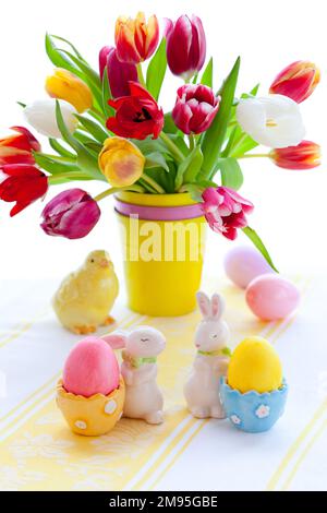 Easter table decorations with bouquet of spring tulips, colorful easter eggs and festive decor. Stock Photo