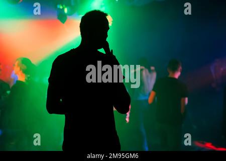 silhouette of the presenter with a microphone on the stage of a nightclub at a concert Stock Photo