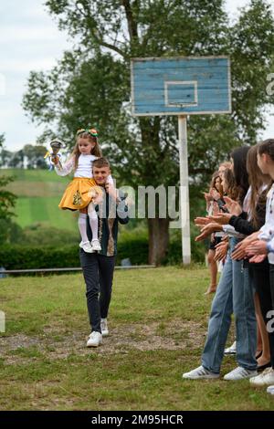Ivano Frankivsk, Ukraine September 1, 2022: the holiday of the first bell in Ukraine, a high school student carries a girl on his shoulders who holds Stock Photo