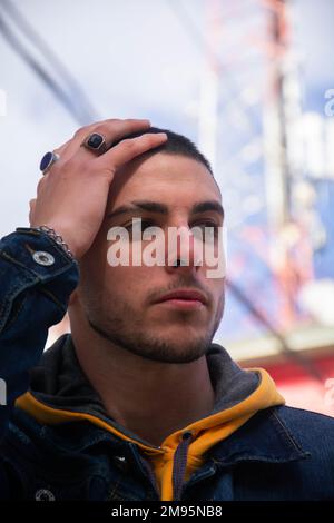 A vertical closeup of a young man touching his head. Stock Photo